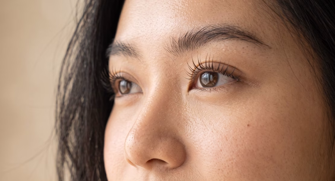 Close-up wajah wanita dengan bulu mata lentik natural hasil perawatan lash lift, menampilkan gaya riasan minimalis dan kulit wajah yang sehat bercahaya."